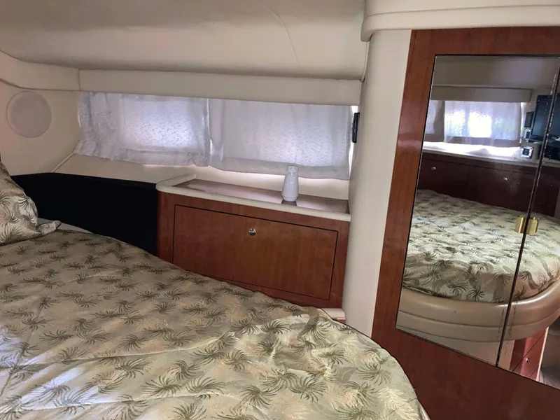 Slide: The Image of 2004 Sea Ray 400 Bridge Deck cabin interior with bed, mirror, and wooden cabinetry. - 25