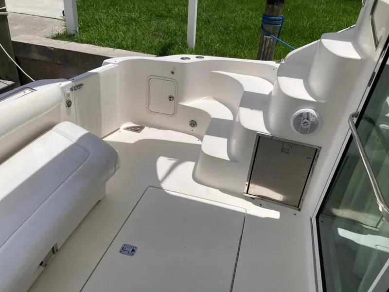 Slide: The Image of 2004 Sea Ray 400 Bridge Deck with white seating and steps, docked near grass. - 6