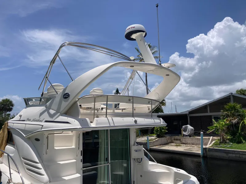Slide: The Image of 2004 Sea Ray 400 Bridge Deck yacht docked under a clear blue sky. - 8