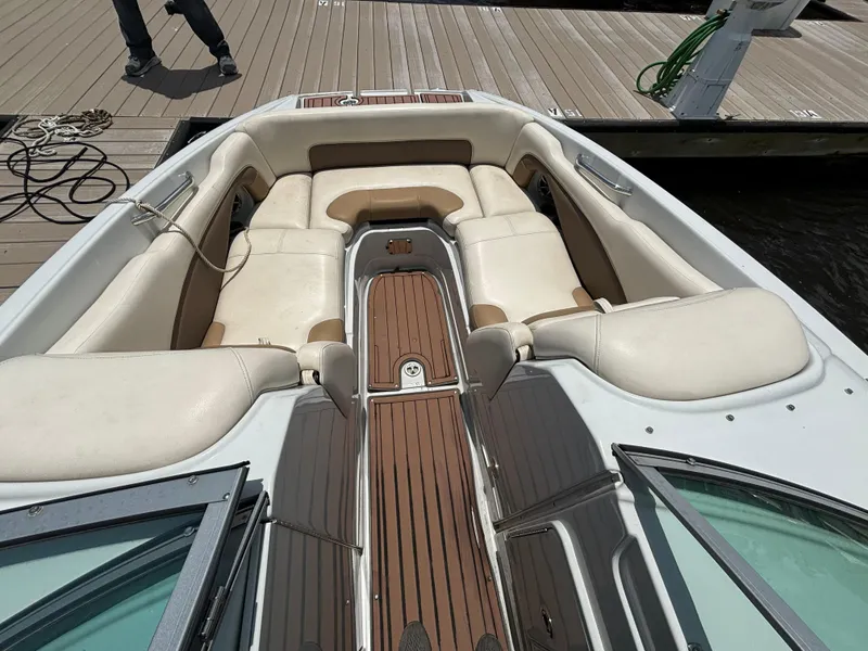Slide: The Image of 2016 Crownline E4 boat interior with beige seating and wooden flooring at a dock. - 11