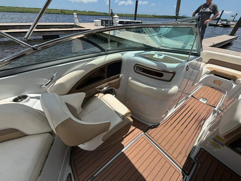 Slide: The Image of 2016 Crownline E4 boat interior with tan seating and wood-style flooring at a dock. - 12