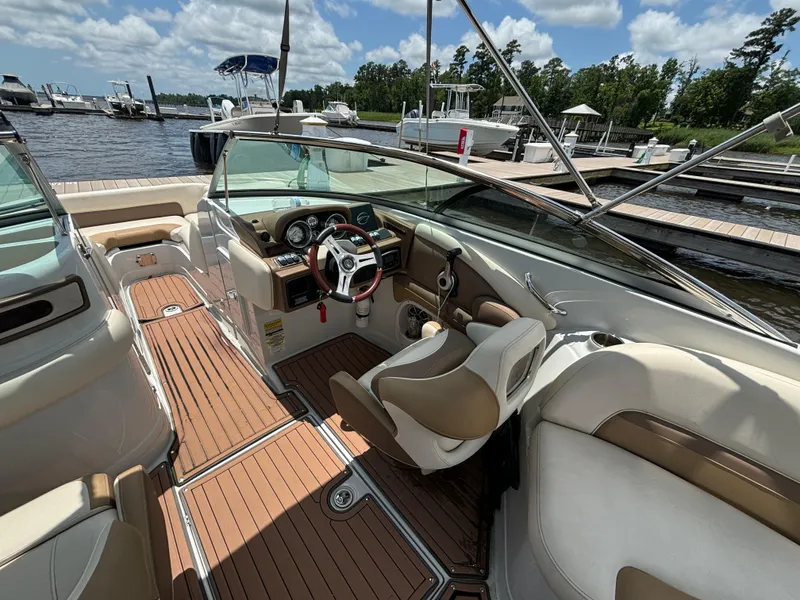Slide: The Image of 2016 Crownline E4 boat interior with luxurious seating and sleek dashboard at a marina. - 15