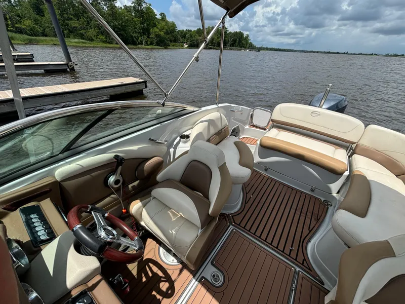 Slide: The Image of 2016 Crownline E4 boat interior with tan seating and wood flooring on a lake. - 9