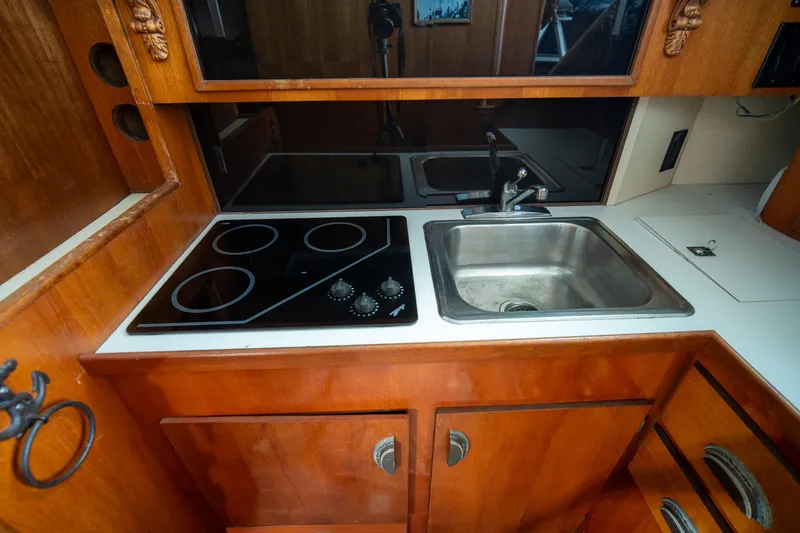 Slide: The Image of 1976 Bertram 42 Convertible kitchen with stove, sink, and wooden cabinetry. - 11