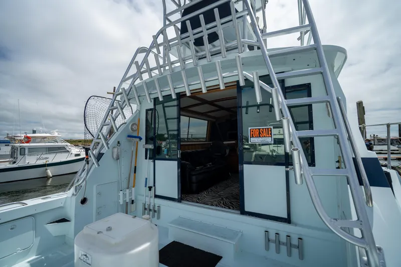 Slide: The Image of 1976 Bertram 42 Convertible yacht for sale at marina, featuring ladder and open cabin. - 13