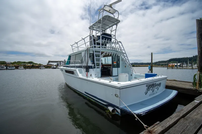 Slide: The Image of 1976 Bertram 42 Convertible boat docked in a marina under cloudy skies. - 15