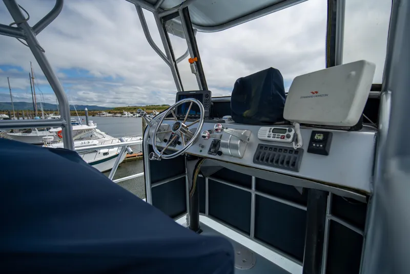Slide: The Image of Helm of a 1976 Bertram 42 Convertible yacht with navigation equipment and marina view. - 17