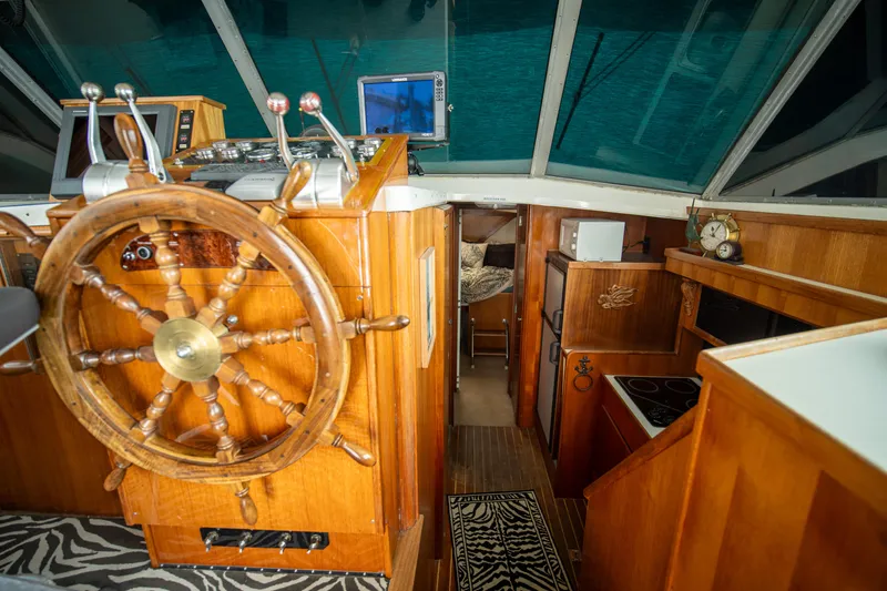 Slide: The Image of 1976 Bertram 42 Convertible interior with wooden helm, nautical decor, and modern navigation equipment. - 4