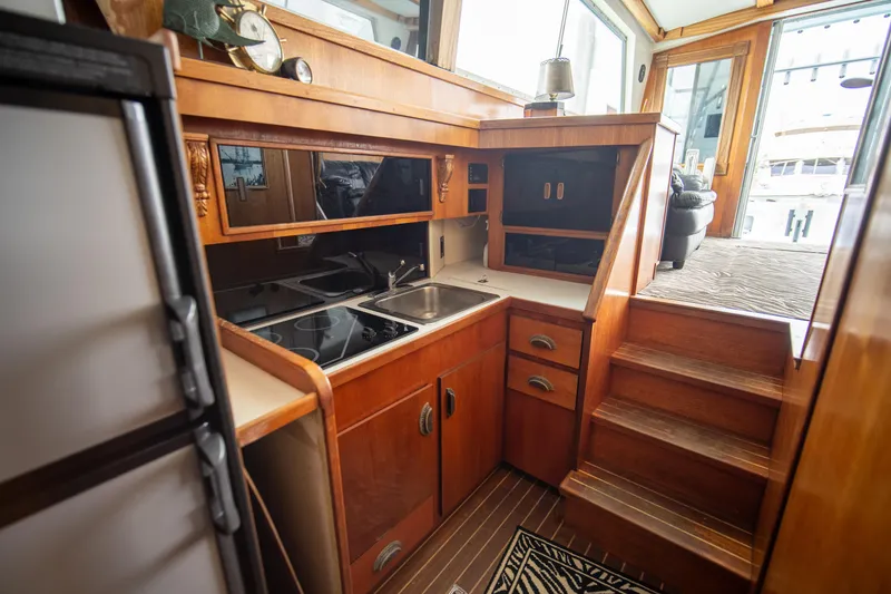 Slide: The Image of 1976 Bertram 42 Convertible yacht interior with wooden cabinetry and compact kitchen area. - 5