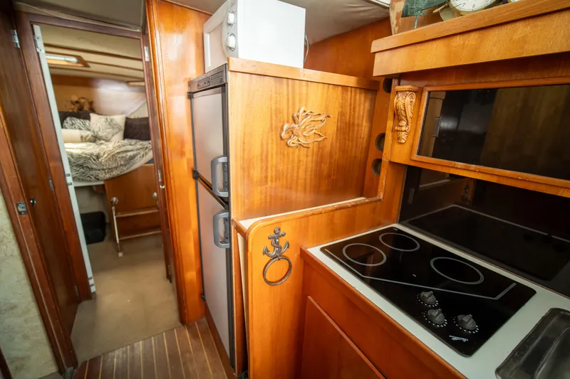 Slide: The Image of 1976 Bertram 42 Convertible yacht interior with wood cabinetry, compact kitchen, and cozy sleeping area. - 7