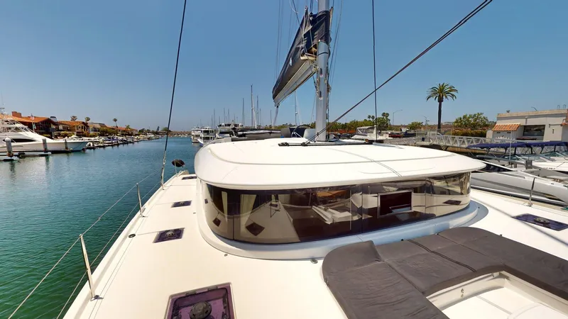 Slide: The Image of 2020 Lagoon 46 catamaran docked in a sunny marina, showcasing sleek design and spacious deck. - 22