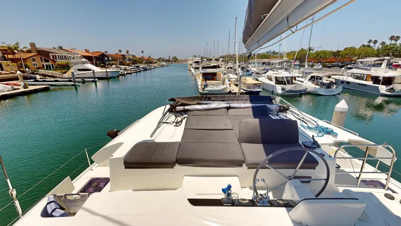 Slide: The Image of 2020 Lagoon 46 catamaran docked in a marina, featuring spacious deck and steering wheel. - 23