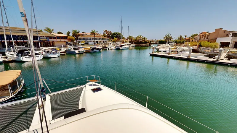 Slide: The Image of Lagoon 46 catamaran docked in a sunny marina, surrounded by boats and palm trees. - 24