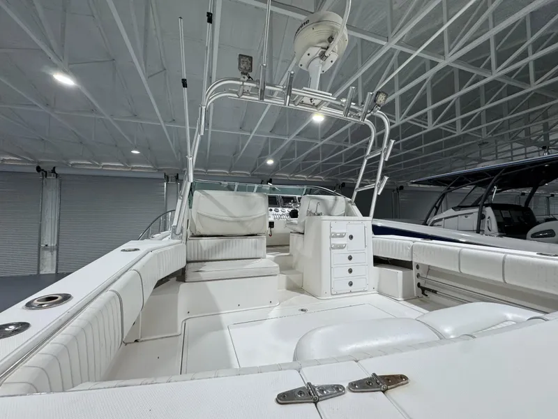 Slide: The Image of 2005 Stamas 310 Express boat interior with white seating and storage, in a well-lit showroom. - 14
