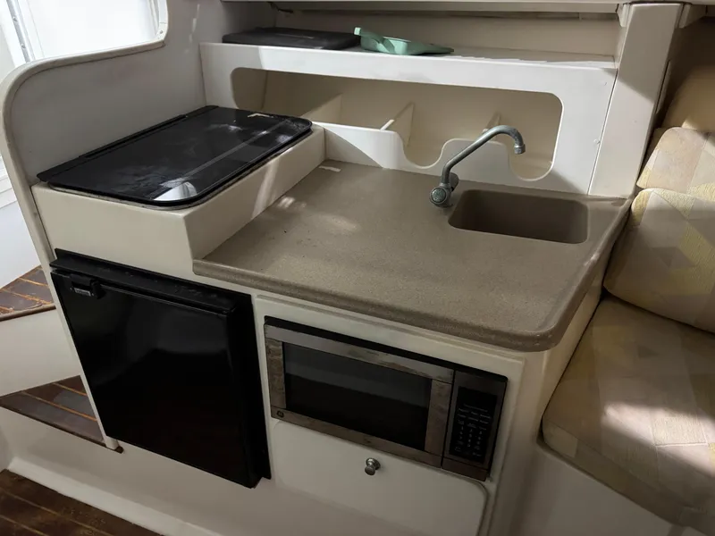Slide: The Image of 2005 Stamas 310 Express boat interior kitchen with sink, stove, fridge, and microwave. - 22
