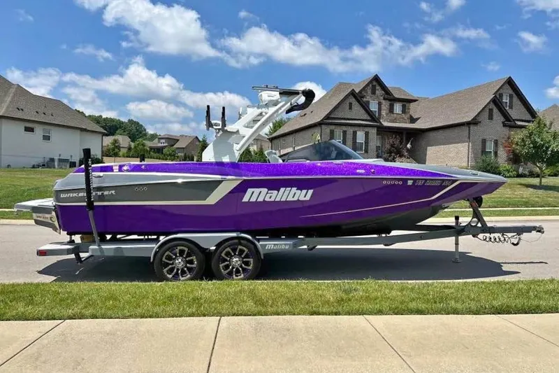 Slide: The Image of 2020 Malibu Wakesetter 24 MXZ boat in vibrant purple on a trailer, suburban background. - 1