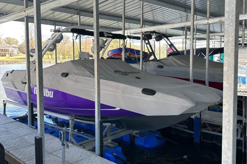 Slide: The Image of 2020 Malibu Wakesetter 24 MXZ boat covered and docked in a marina. - 2