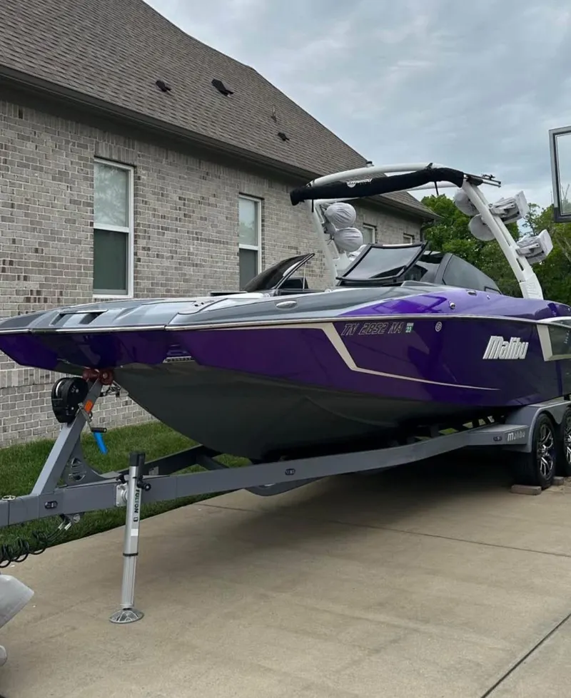 Slide: The Image of 2020 Malibu Wakesetter 24 MXZ boat in purple on a trailer, parked in a driveway. - 7