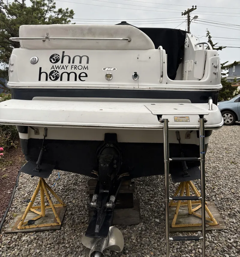 Slide: The Image of 2003 Crownline 262 CR boat on stands, rear view with ladder and "Ohm Away From Home" text. - 10