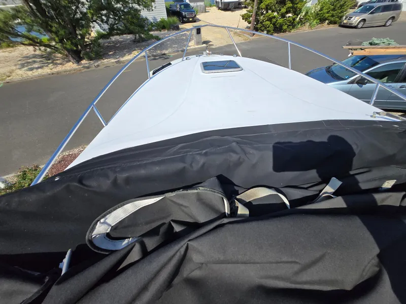 Slide: The Image of 2003 Crownline 262 CR boat bow view with cover, parked in a residential area. - 15