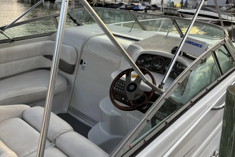 Slide: The Image of 2003 Crownline 262 CR boat interior with steering wheel and seating, docked by the water. - 18