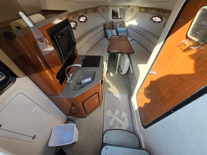 Slide: The Image of Interior of 2003 Crownline 262 CR boat with kitchenette and seating area. - 2