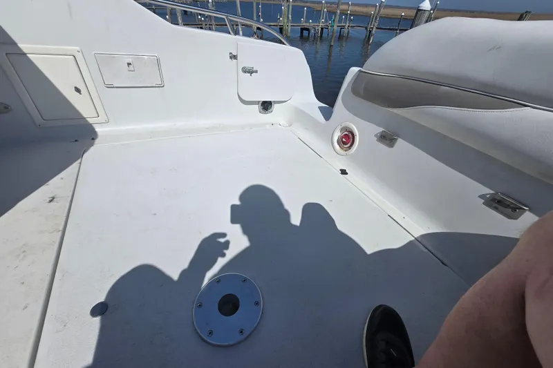 Slide: The Image of 2003 Crownline 262 CR boat deck with shadows and seating, dock in background. - 24