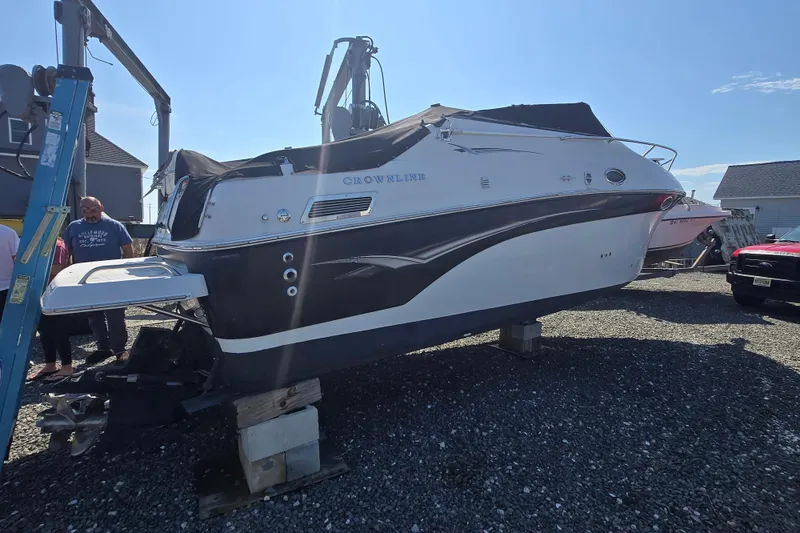 Slide: The Image of 2003 Crownline 262 CR boat on blocks, outdoor setting, clear sky. - 25