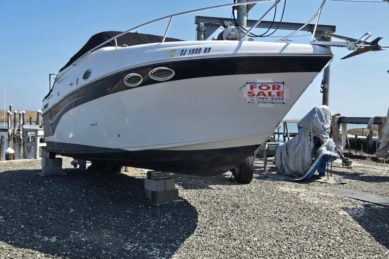 Slide: The Image of 2003 Crownline 262 CR boat for sale, displayed on blocks at a marina. - 26