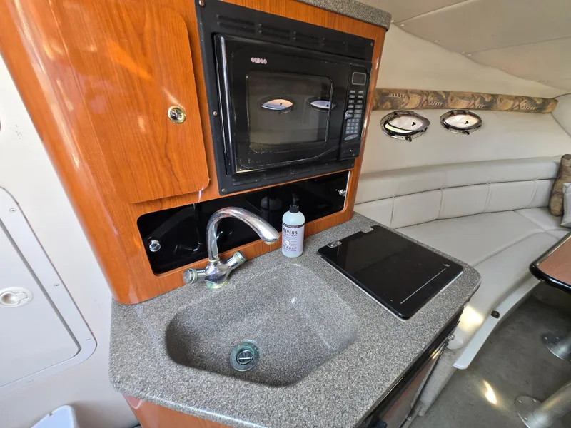 Slide: The Image of 2003 Crownline 262 CR boat interior with kitchenette, sink, and microwave. - 5