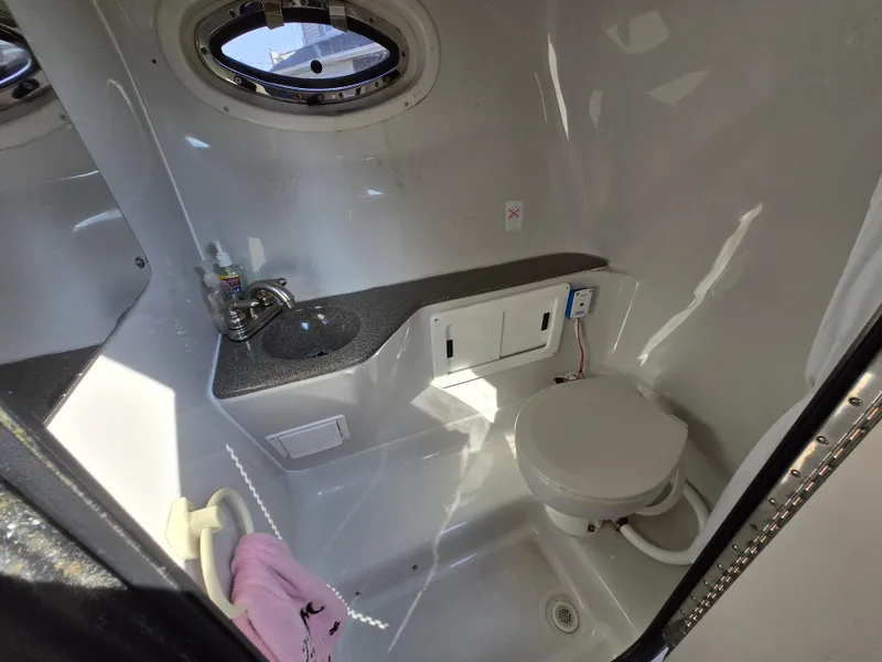 Slide: The Image of 2003 Crownline 262 CR boat bathroom with sink, toilet, and porthole window. - 7