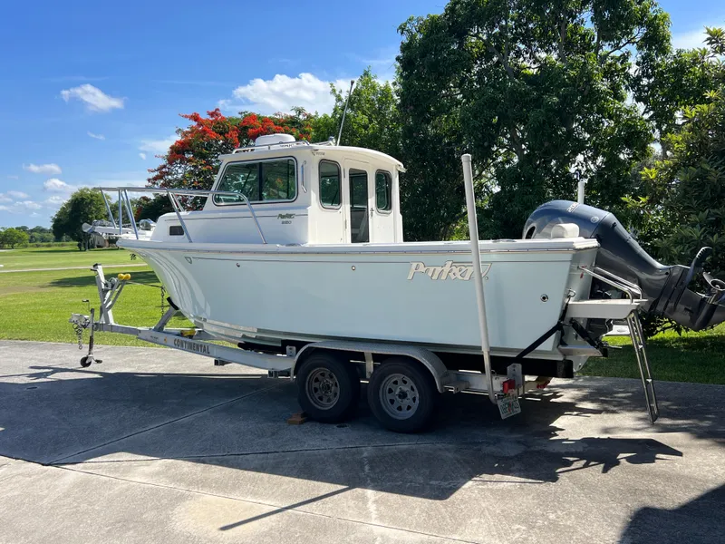 Slide: The Image of 2021 Parker 2120 boat on trailer, parked outdoors with trees and blue sky background. - 10