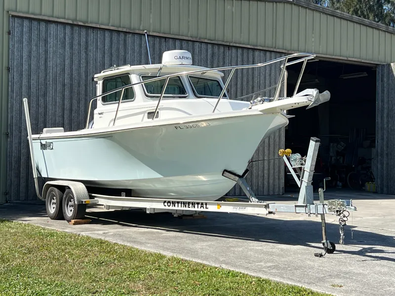 Slide: The Image of 2021 Parker 2120 boat on trailer outside a metal garage. - 15