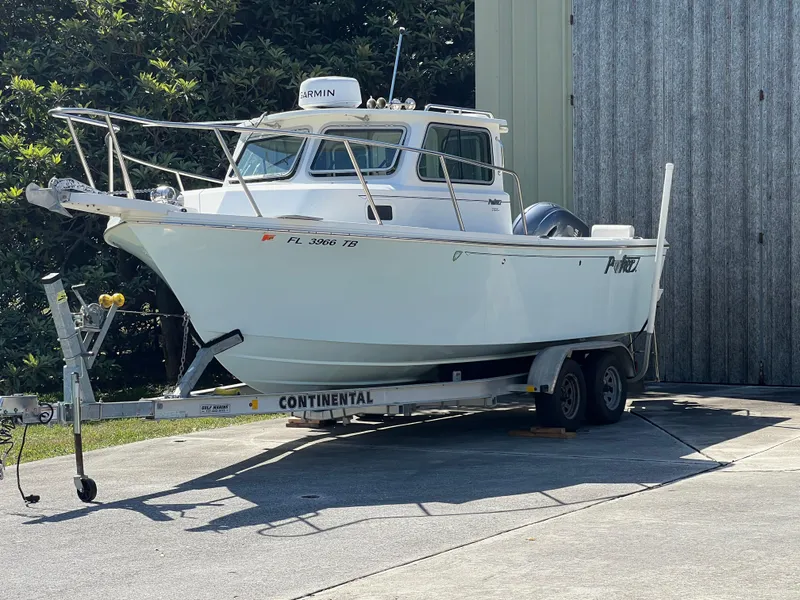 Slide: The Image of 2021 Parker 2120 boat on trailer, parked outdoors near a metal building. - 16