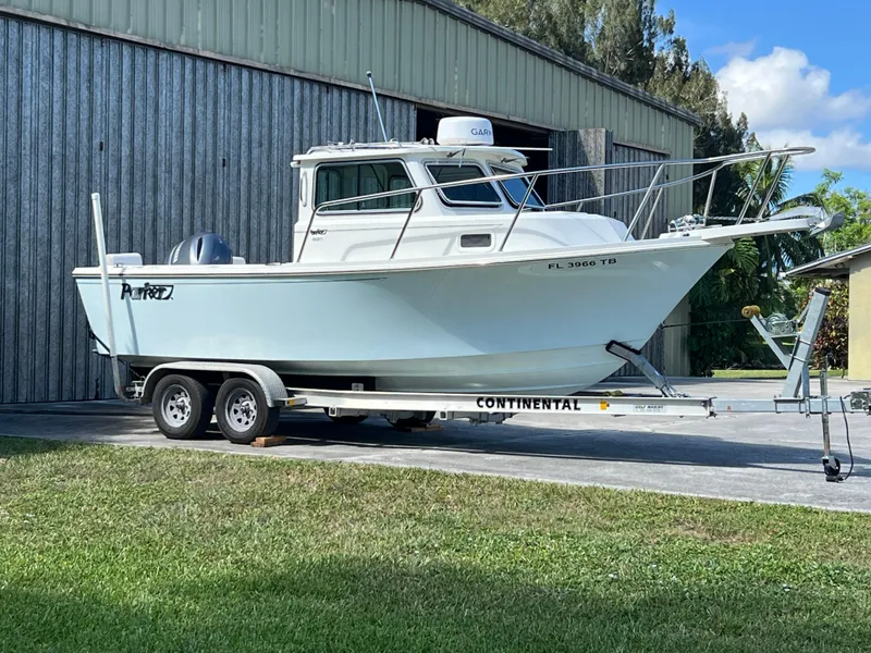 Slide: The Image of 2021 Parker 2120 boat on trailer outside a metal building. - 18