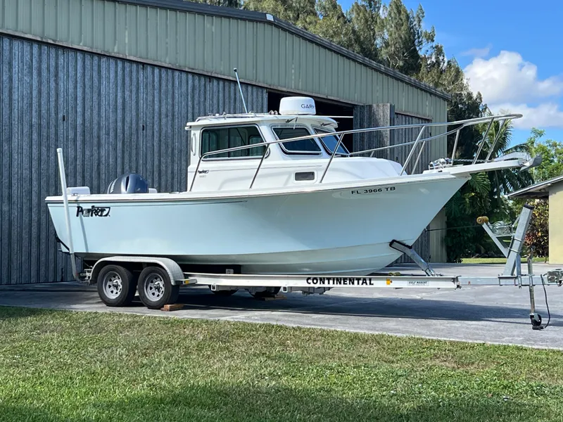 Slide: The Image of 2021 Parker 2120 boat on trailer, parked outside a metal building. - 19