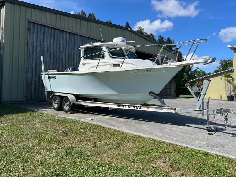Slide: The Image of Parker 2120 boat on trailer, parked outdoors, sunny day, 2021 model. - 20