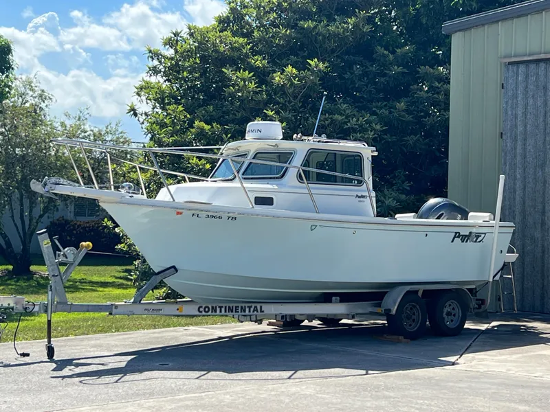 Slide: The Image of 2021 Parker 2120 boat on trailer, parked outdoors near a building. - 21