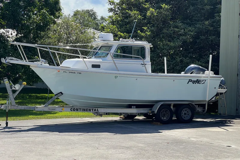Slide: The Image of 2021 Parker 2120 boat on trailer, parked outdoors near trees. - 22