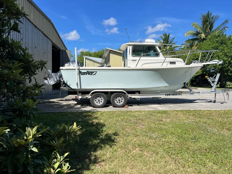 Slide: The Image of 2021 Parker 2120 boat on trailer, parked outdoors near a building, under clear blue sky. - 4