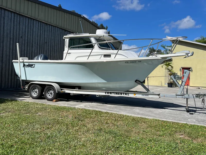 Slide: The Image of 2021 Parker 2120 boat on trailer, parked outdoors near a building. - 6
