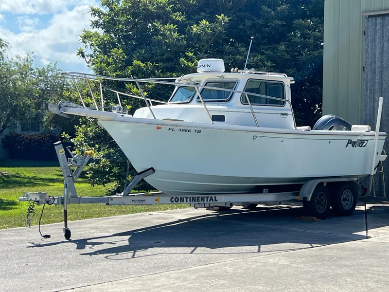 Slide: The Image of 2021 Parker 2120 boat on trailer, parked outdoors near greenery. - 8