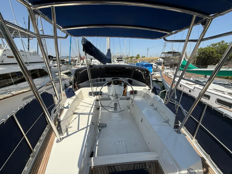 Slide: The Image of Cockpit view of 1985 Nauticat 43 sailboat docked in marina, featuring steering wheel and canopy. - 10