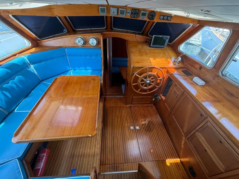 Slide: The Image of Interior of 1985 Nauticat 43 sailboat with wooden helm, blue seating, and navigation instruments. - 17