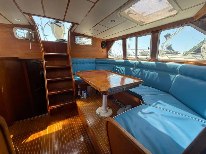 Slide: The Image of Interior of 1985 Nauticat 43 sailboat with blue cushioned seating and wooden table. - 18