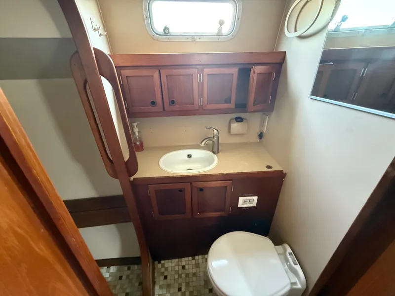 Slide: The Image of 1985 Nauticat 43 yacht bathroom with wooden cabinets, sink, and toilet. - 23