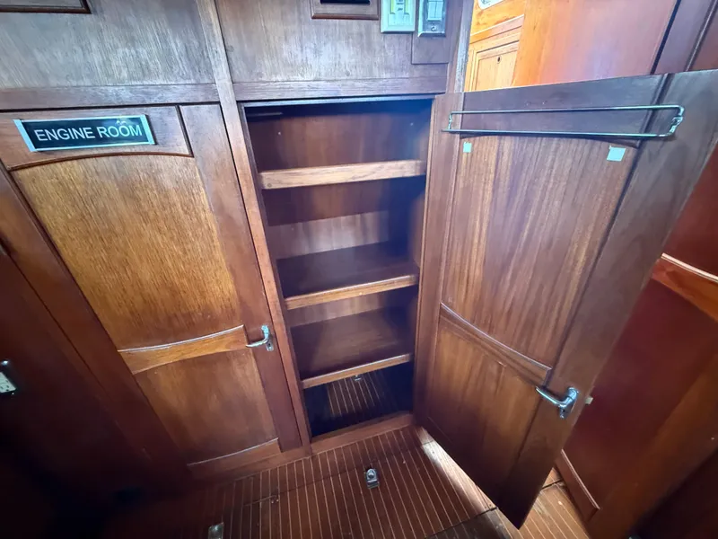 Slide: The Image of Wooden interior of 1985 Nauticat 43 yacht, featuring open storage shelves and engine room access. - 25