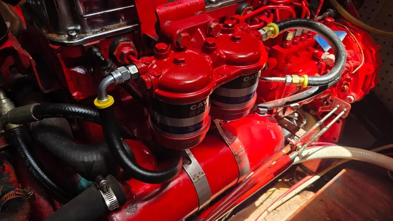 Slide: The Image of Engine components of a 1985 Nauticat 43, featuring red filters and hoses. - 34