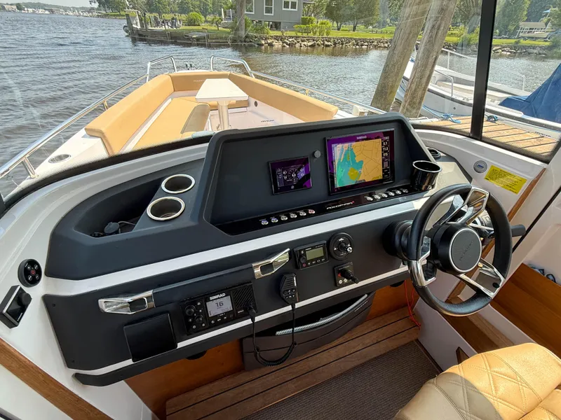 Slide: The Image of 2021 Axopar 28 CABIN boat dashboard with navigation screens and steering wheel. - 17