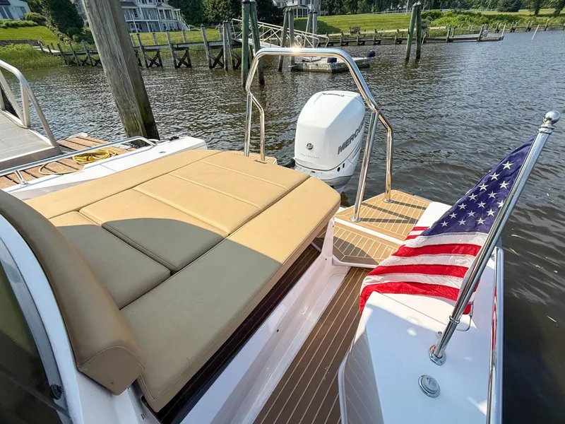 Slide: The Image of 2021 Axopar 28 CABIN boat with American flag, docked by a scenic waterfront. - 22